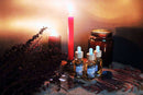 Ätherisches Lilith Oil Ritualöl von Ayamani Naturals mit Mondstein- und Tigeraugenkristallen, in einer dunklen Flasche auf einem Ritualtuch.