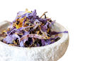 Ein rustikaler weißer steinschale mit getrockneten lila und gelben blauer lotus blütenblätter von ayamani naturals für spirituelle rituale