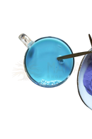 Ein klarer glasbecher mit ayamani naturals blauer samt latte aus botanischer blue butterfly und einem goldfarbenen rührstab
