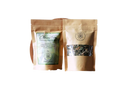 Two brown paper tea bags with clear windows showing dried herbs labeled ayamani naturals claritea pineal gland decalcifying herbal tea