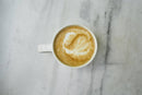 Golden Chai Latte mit Reishi von Ayamani Naturals in einer Tasse, cremig und goldgelb, mit Gewürzen und Reishi-Pilzen.