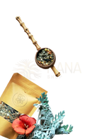 A wooden spoon with bamboo handle filled with dried green and orange leaves of ayamani naturals sacral chakra herbal tea