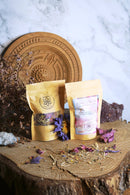 Ayamani Naturals Crown Chakra Kräutertee mit Lotus, Rose und Ginseng, 25g, in einer Teetasse und Teekanne auf Holzuntergrund