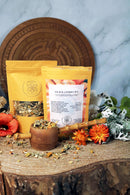Ayamani Naturals Sakralchakra Kräutertee mit weiblicher Kräutermischung in einer Teekanne und Tasse, naturbelassene Kräuter.