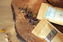 Ayamani Naturals Manifest Tee, eine Kräutermischung in einer Teetasse mit frischen Kräutern und Blättern, fördert Inspiration und Manifestation