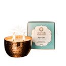 Eine lit pitta aqua oud duftkerze von ayurveda specialist aus gehämmertem gold in kupferfarbenem metallhalter mit zwei flammen