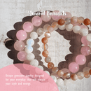 Zwei Perlenarmbänder aus rosa Rosenquarz und gelbem Sonnenstein, fotografiert auf einem weißen Holzhintergrund.