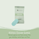 Eine Nahaufnahme auf hellgrünem Hintergrund, die einen versiegelten Folienbeutel mit COSMEAU KÜCHE ZITRONE Reinigungs-Tabs zeigt, davor liegt eine einzelne hellblaue, sprudelnde Tablette. Darunter steht der Text: „Küchenreiniger Zitrone / Entfernt Fett und Speisereste von Ihrem Kochfeld, Arbeitsplatten und Boden.“