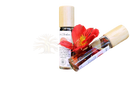 Zwei klare glas rollerflaschen mit holzkappen gefüllt mit ayamani naturals root chakra öl und getrockneten kräutern muladhara chakra