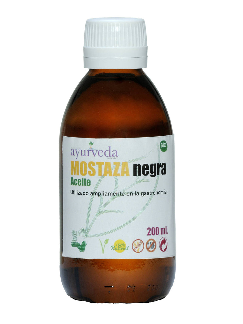 Eine braune Glasflasche mit weißem Schraubverschluss, beschriftet mit "Ayurveda autentico MOSTAZA negra Aceite" (Schwarzes Senföl). Das Etikett zeigt ein grünes Blattmuster, "200 ml", "100% Natur", "Sin Gluten" und "OMG" (gentechnikfrei) Symbole.