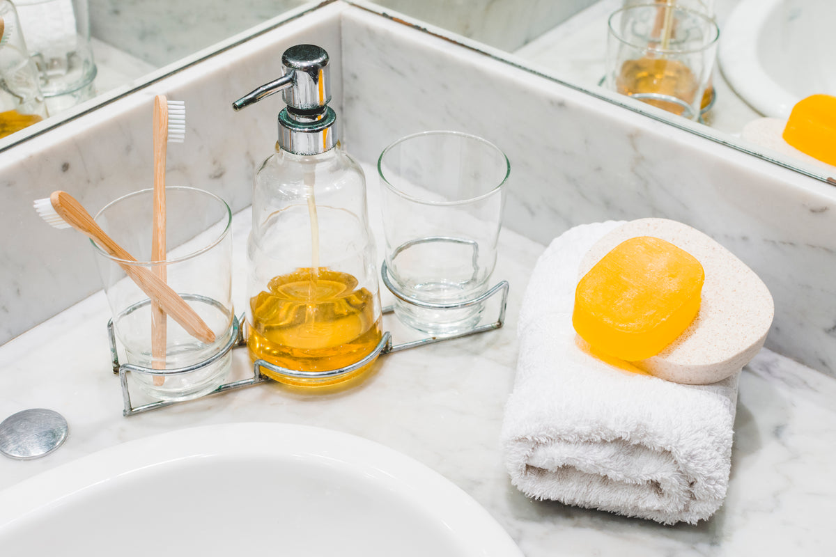 Bio-Seife auf weißem Handtuch neben Seifenspender und Zahnbürsten im Badezimmer.