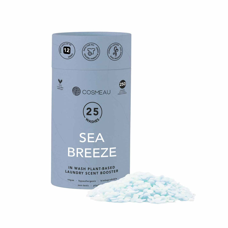 Cosmeau In-Wash Wäscheduft-Booster im Duft "Sea Breeze", 250 Gramm (25 Wäschen), hebt seinen langanhaltenden Duft (bis zu 12 Wochen), Sicherheit für alle Farben/Stoffe und Dual-Duft-Technologie hervor. Es ist auch vegan, hypoallergen, biologisch abbaubar, ungiftig und plastikfrei. Ein Haufen hellblauer Duftperlen liegt neben der Verpackung.
