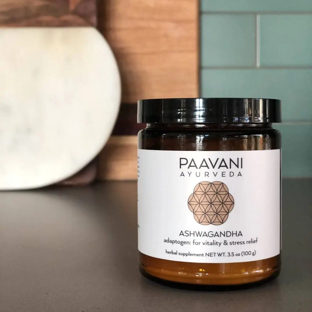 Ein schlankes bernsteinfarbenes glas mit schwarzem deckel und weißem etikett paavani ayurveda bio ashwagandha pulver organic ashwagandha powder für energie und stressabbau