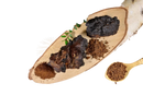 Dunkle, raue stücke organischer chaga und feines braunes pulver auf hellen holzbrett für bio chaga kapseln