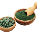 Bio chlorella pulver in grün in einer holzschale mit holzlöffel und chlorella vulgaris tabletten in schale