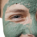 Person mit grüner bio gesichtsmaske mit algenextrakt und heilender tonerde für reine und weiche haut
