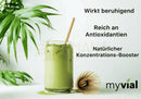 Ein klares glas mit bio matcha pulver iced tea in grün aus japan mit holzstrohhalm und bambusbesen für achtsame energie