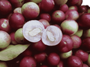 Halbe glänzende rote und grüne frucht mit durchscheinendem weißem inneren und zwei samen bio vitamin c pulver camu camu bio