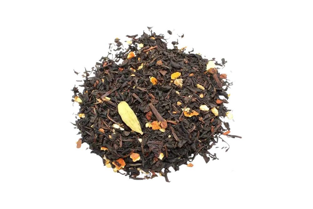A pile of dark loose-leaf black magic blend tea with orange and brown spices and a green cardamom pod nestled among the leaves
