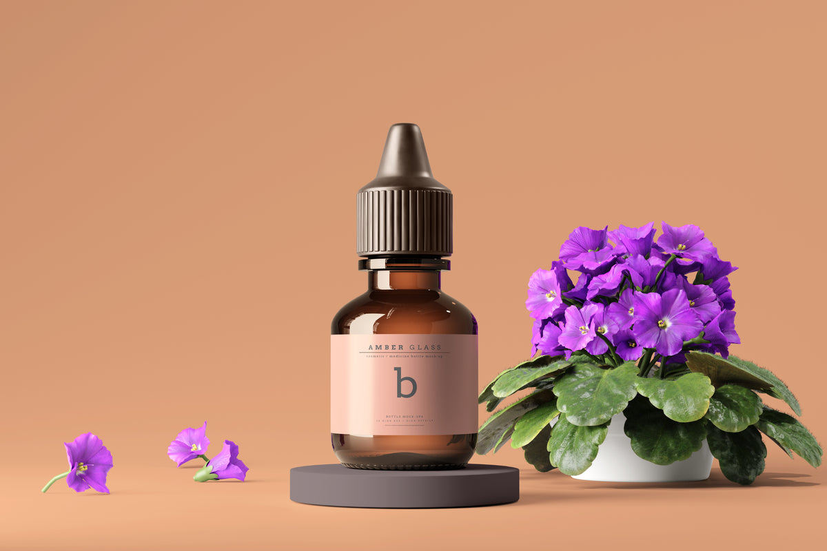 Braune Amber-Glasflasche mit Pipette neben violetten African Violet Blumen.
