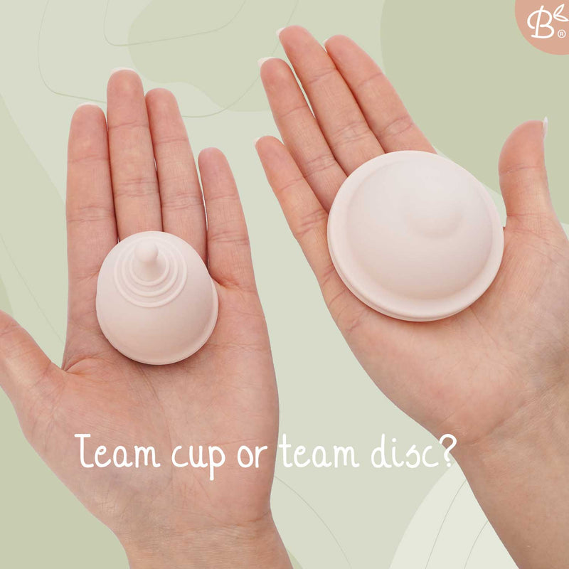 Die Hände einer Frau halten in der einen Hand eine rosa Menstruationstasse und in der anderen eine Menstruationsscheibe, mit der Frage "Team Tasse oder Team Scheibe?".