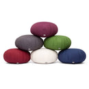 Ein Stapel von sechs runden Meditationskissen, genannt "Zafus", in verschiedenen Farben: Lila, Grau, Grün, Rot, Creme und Dunkelblau, alle mit dem "Bodhi"-Label.