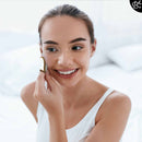 Eine lächelnde Frau mit sauberem Gesicht reinigt sanft ihre Wange mit einem weißen wiederverwendbaren Wattepad.