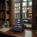 Ein kleiner, mehrstufiger Steinbrunnen auf einer hölzernen Fensterbank in einer gemütlichen Bibliothek, während es draußen regnet.
