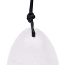 Nahaufnahme eines polierten, glatten, weißen oder klaren Kristall-Ei-Anhängers, der die Oberseite zeigt, durch die eine schwarze Kordel geknotet ist.