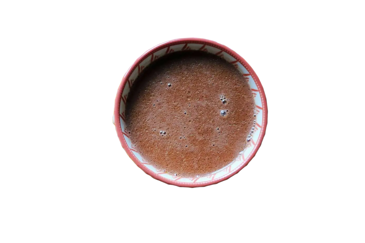 Ayamani Naturals Choc Me Up Adaptogener Kakao- und Pilz-Mocha-Tee mit Reishi und Chaga, in einer Tasse mit Kakaobohnen.