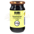 Ein dunkles glasgefäß mit kupferfarbenem deckel und gelbem etikett von nimi ayurveda für chyawanprash premium traditionelle ayurveda-rezeptur mit amla frucht