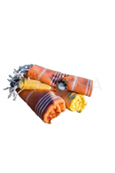 Three rolled classic hamam towels in orange and yellow with white stripes and fringed edges, traditionally woven hamam hand towels