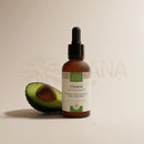 Braune glasflasche mit schwarzem tropfverschluss und weißem etikett mit grünen akzenten avocadoöl regenerierendes öl für gesicht haar und körper von comptoir des huiles