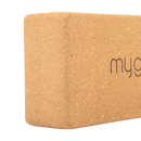 A tan cork yoga block with a subtle myg logo embossed on the surface from mana shop