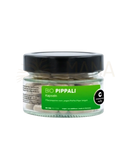 A clear glass jar with black lid containing white cosmoveda pippali capsules labeled bio pippali kapseln langer pfeffer ayurveda