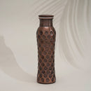 Eine dunkle, gehämmerte Kupferwasserflasche mit sechseckigem Wabenmuster, unter weichem Licht mit subtilem Schatten.