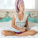 Eine Frau mit einem rosa Handtuch um den Kopf sitzt im Schneidersitz auf einem Bett und hält eine kleine Flasche PAAVANI-Öl.