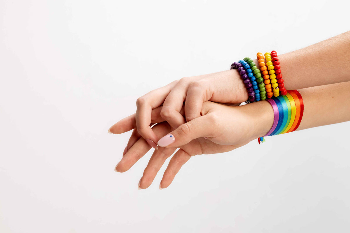Bunte Regenbogen-Perlenarmbänder und ein farbenfrohes Armband an den Handgelenken.