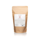 Die Rückseite eines stehenden braunen Papierbeutels mit Paavani Ayurveda Rosenblüten vor einem weißen Hintergrund.