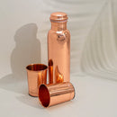 Polierte Kupfer-Wasserflasche, die hinter zwei Kupferbechern vor einem neutralen Hintergrund steht.