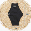 Eine schwarze wiederverwendbare Binde von Bamboozy (Medium Light) auf einer gewebten Matte, mit Maßen von 26cm Länge und 18cm Breite, ausgestattet mit Druckknöpfen