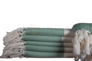 Stack aus grünen und cremefarbenen ecobain couture towel türkisches baumwolle badetüchern im herringbone muster mit fransen