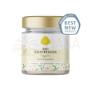Ein klarer glasbehälter mit goldverschluss enthält eliah sahil zahnpulver ingwer bio mit austria bio garantie label
