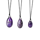 Drei polierte eiförmige Amethyst-Steine hängen an schwarzen Schnüren.