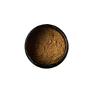 Draufsicht auf ein Glasgefäß, das mit braunem Tridoshic Spice Blend Pulver gefüllt ist.