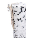 Nahaufnahme einer weißen, mit schwarzen Flecken gesprenkelten Kerze und einem kleinen Etikett.