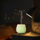 Aromatherapie-Diffusor in einem abgedunkelten Schlafzimmer, der hell leuchtet und Dampf abgibt.