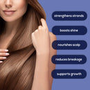 Eine Frau mit langen, glatten, glänzenden braunen Haaren fasst sich vor einem lila Hintergrund in die Haare. Schwimmende Textfelder listen die Produktvorteile auf: "strengthens strands" (stärkt die Strähnen), "boosts shine" (erhöht den Glanz), "nourishes scalp" (nährt die Kopfhaut), "reduces breakage" (reduziert Haarbruch), "supports growth" (unterstützt das Wachstum).