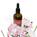 Ein dunkelbernsteinfarbener glasflakon mit schwarzem tropfverschluss und rotem label oils steht unter rosa und weißen blumen glamour premium ätherische öle mana shop