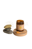 Braunes glasgefäß mit paavani ayurveda goldene milch pulver auf holzunterlage neben glatten steinen im mana shop